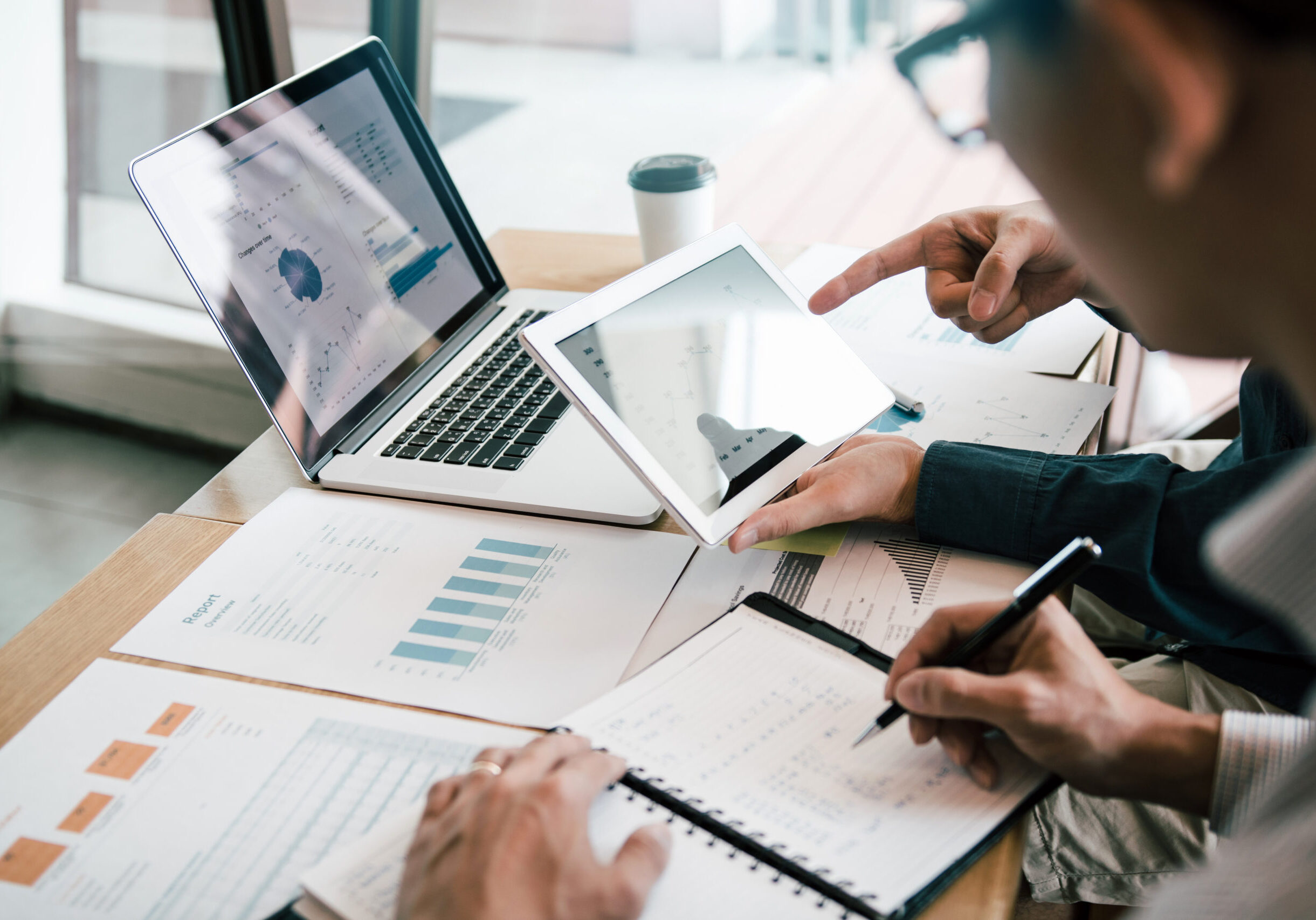 Business partnership coworkers using a tablet to analysis graph company financial budget report and cost work progress and planning for future in office room.